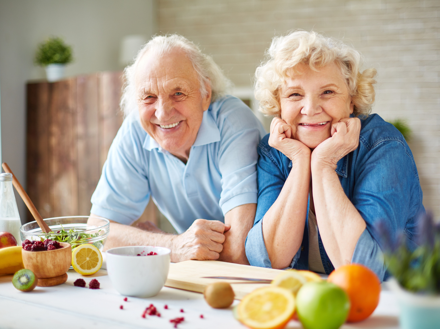 Happy senior man and woman looking at camera in the kitchen